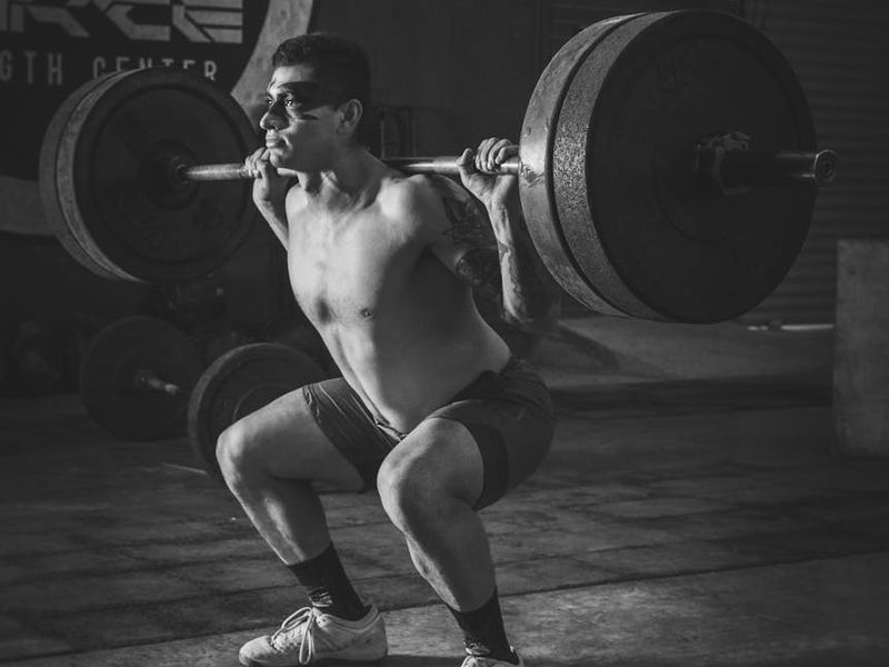Athletic male hands holding a heavy barbell firmly.